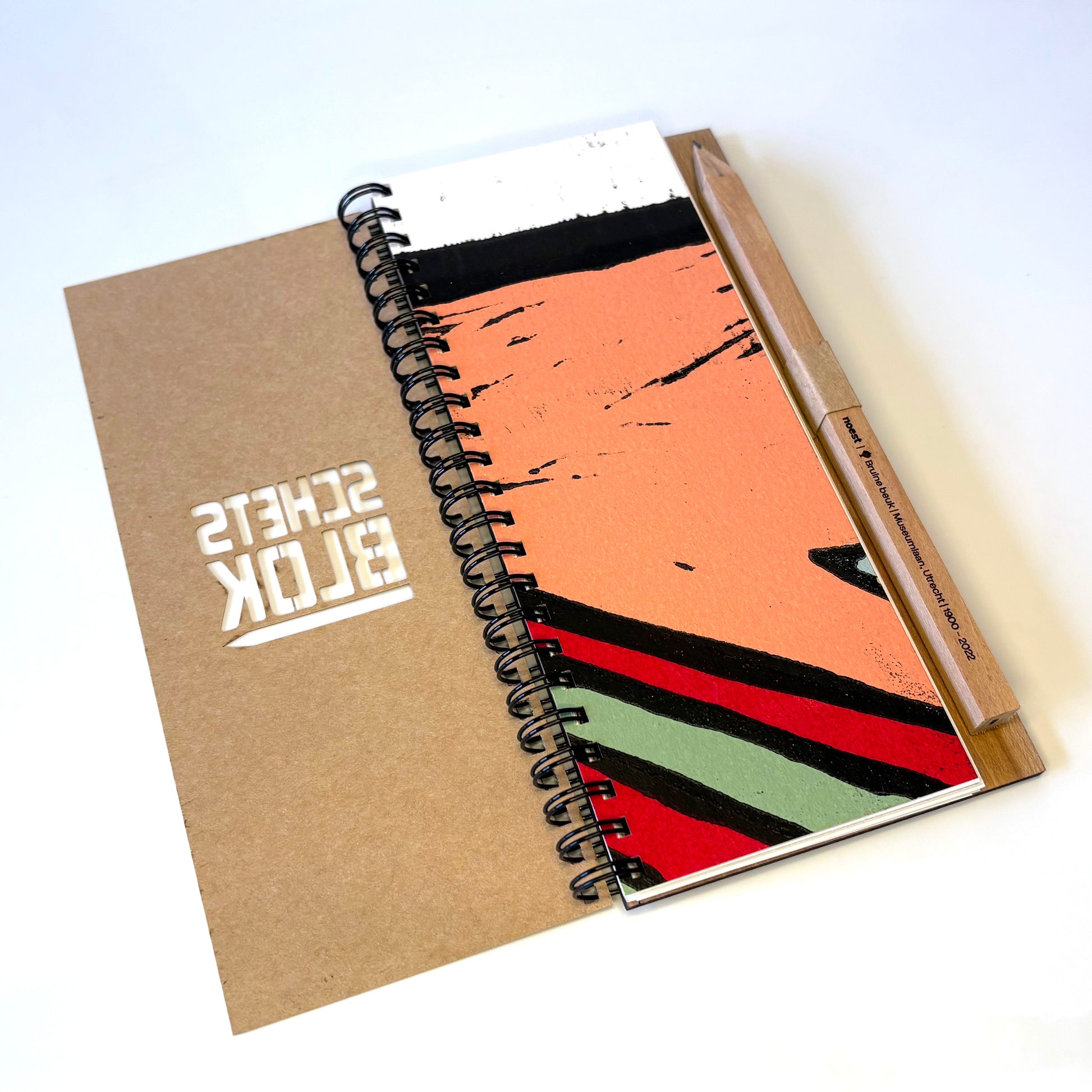 Het schetsblok opengeklapt op tafel, toont gerecycled papier en gepersonaliseerd potlood